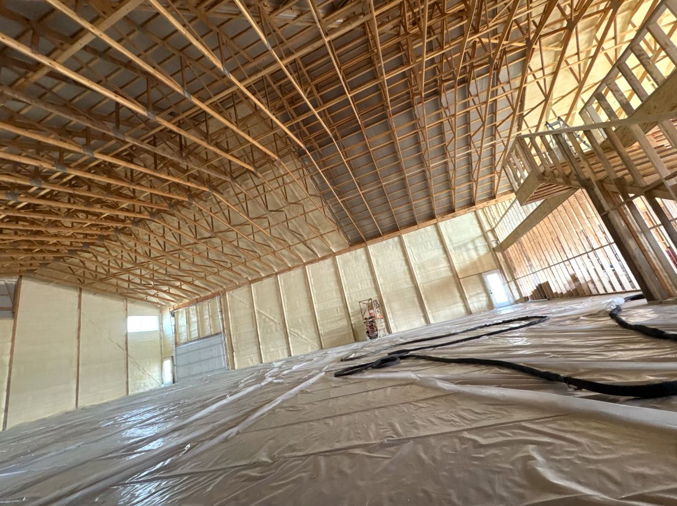 Mid-job, with the floor covered in plastic and the spray hose run through the building.
